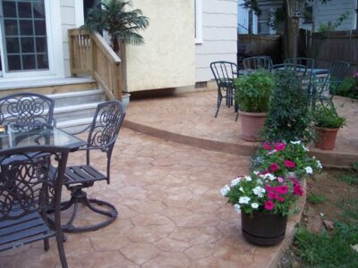 Random Stone concrete job by Concrete by Design Random Stone concrete patio with table, chairs, and potted flowers