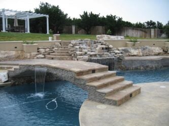 Old Granite Seamless job by Zeevaert Pools concrete pool deck with bridge going across pool